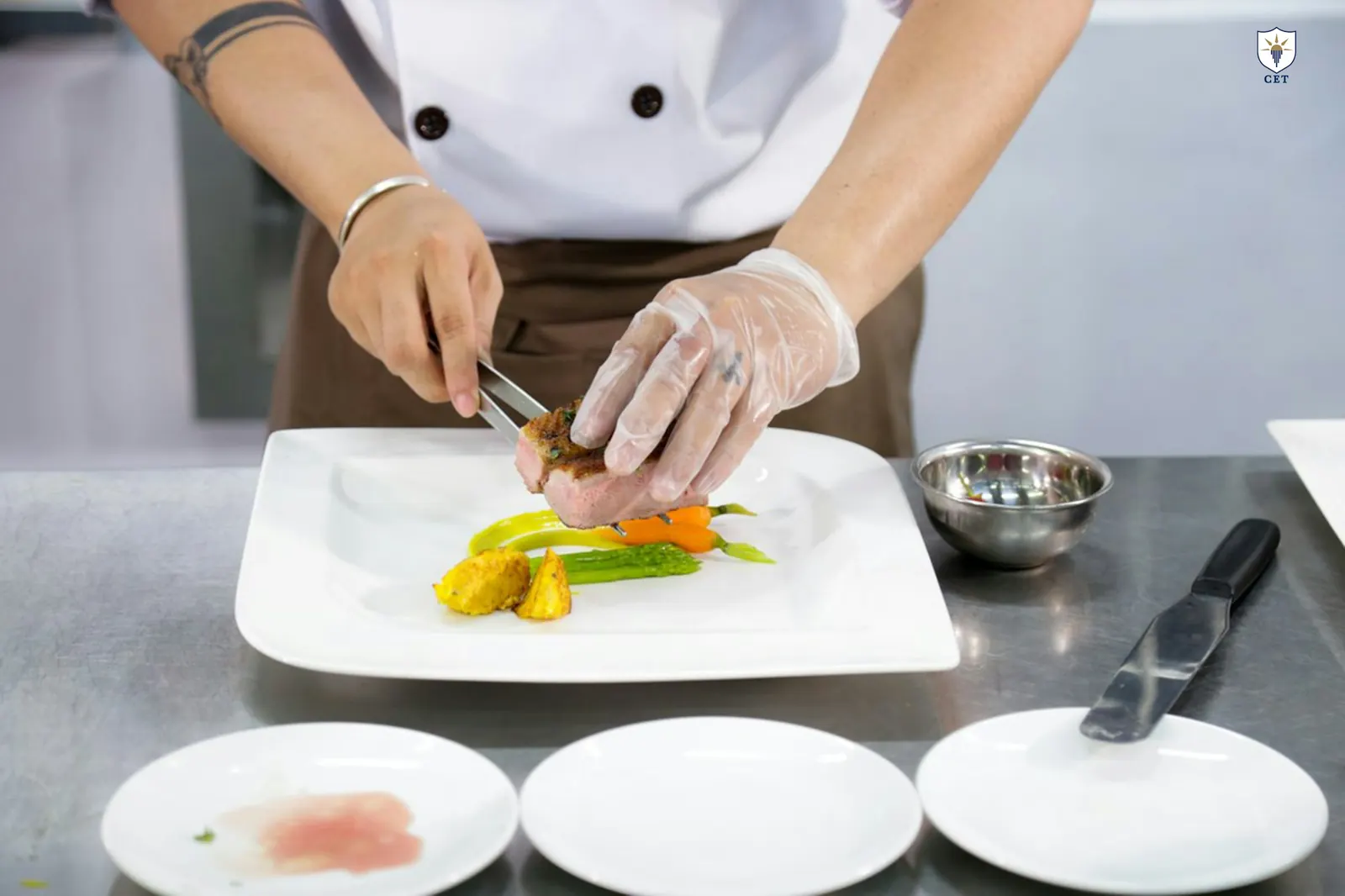 Chef in gloves plating a dish on a white plate